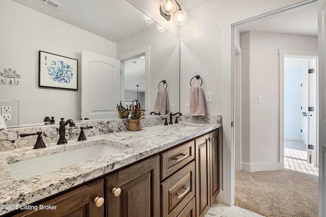 full bath with double vanity, baseboards, visible vents, and a sink