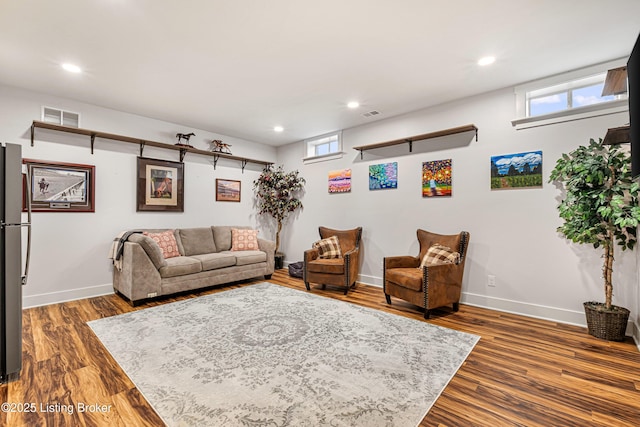 living room with dark wood-style floors, visible vents, and baseboards