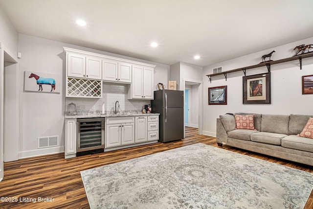 kitchen featuring wine cooler, freestanding refrigerator, visible vents, and a sink