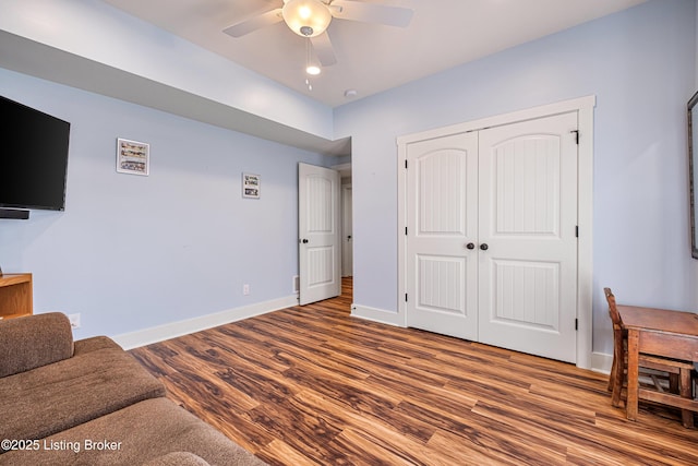 interior space with wood finished floors, a ceiling fan, and baseboards