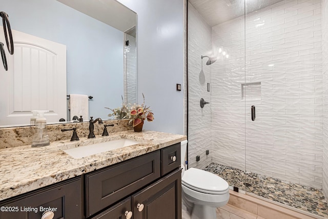 full bathroom with a stall shower, vanity, and toilet