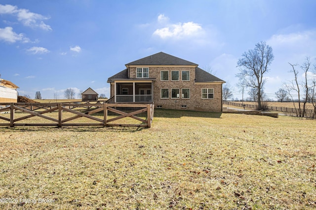 rear view of property with brick siding, fence, a sunroom, a lawn, and crawl space