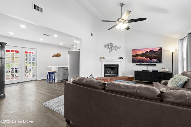 living area featuring visible vents, a fireplace, a ceiling fan, and dark wood-style flooring