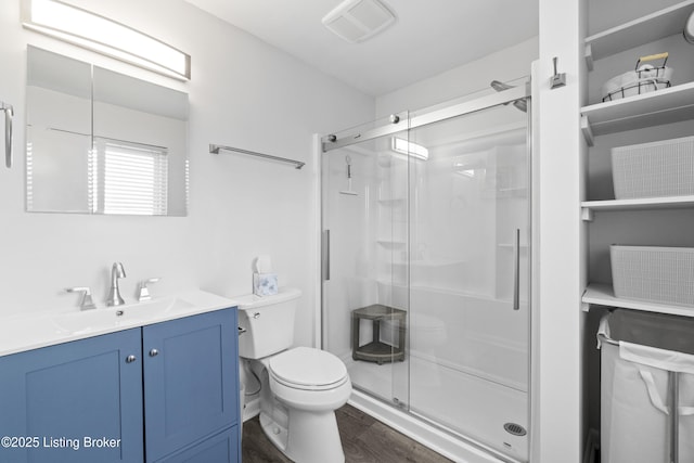 bathroom with visible vents, a stall shower, toilet, and wood finished floors