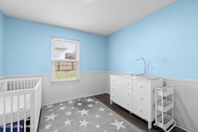 bedroom with wood finished floors and wainscoting