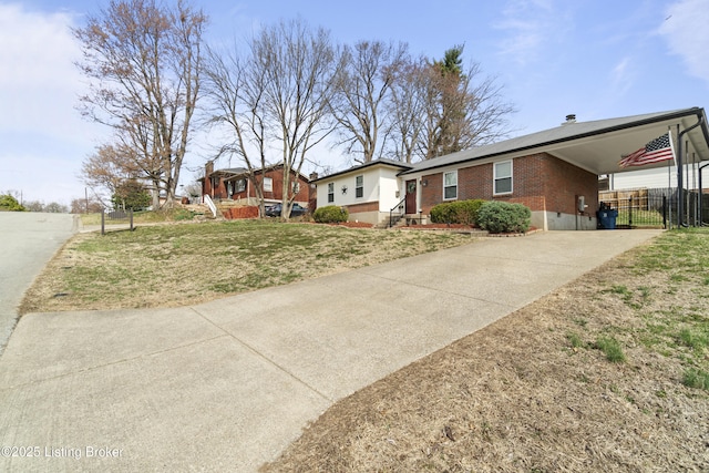 ranch-style house with an attached carport, fence, concrete driveway, a front lawn, and brick siding