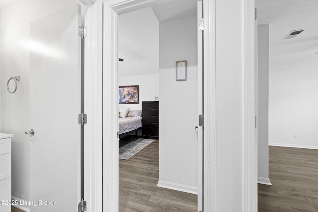 bathroom with wood finished floors, baseboards, and a textured ceiling