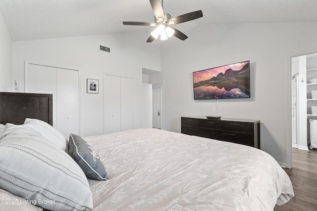 bedroom featuring wood finished floors, visible vents, ceiling fan, vaulted ceiling, and two closets