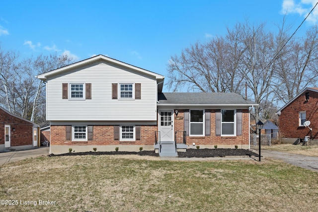 split level home with driveway, brick siding, and a front yard