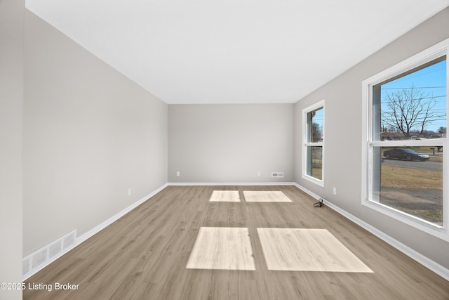 spare room featuring baseboards, visible vents, and wood finished floors