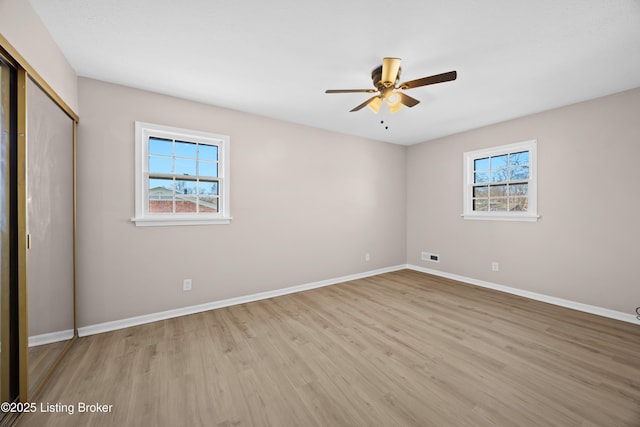 unfurnished bedroom featuring a closet, multiple windows, wood finished floors, and baseboards