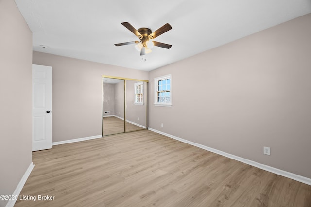 unfurnished bedroom featuring ceiling fan, light wood finished floors, a closet, and baseboards