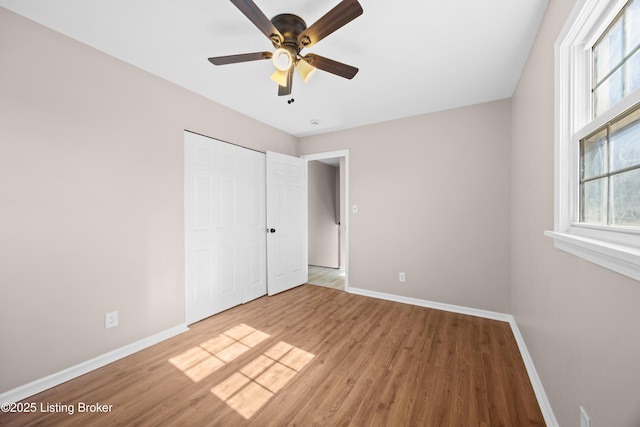 unfurnished bedroom with a ceiling fan, a closet, baseboards, and wood finished floors