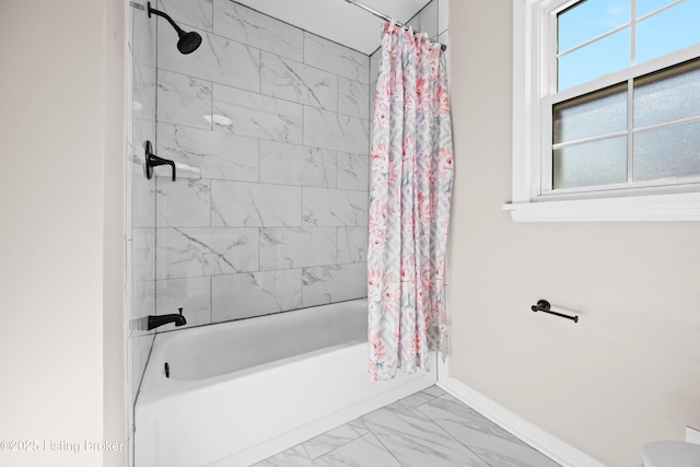 full bath featuring marble finish floor, shower / tub combo, toilet, and baseboards