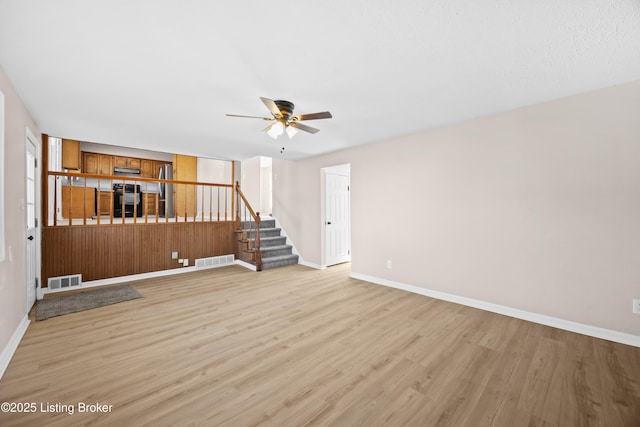 unfurnished living room featuring stairway, baseboards, visible vents, and light wood-style floors