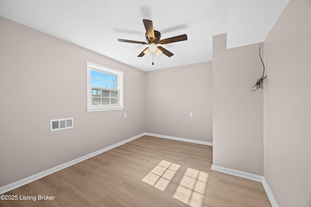 spare room featuring light wood finished floors, baseboards, visible vents, and a ceiling fan