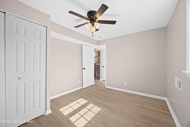 unfurnished bedroom with a ceiling fan, light wood-type flooring, visible vents, and baseboards