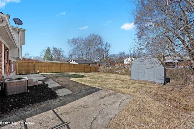 view of yard with a storage unit, fence, central AC, and an outdoor structure