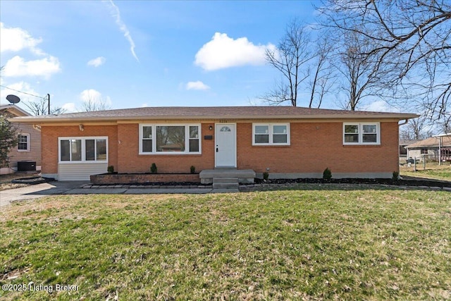 ranch-style home featuring brick siding, central AC unit, and a front yard