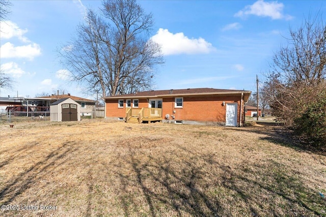 back of house with fence, a yard, an outdoor structure, a storage unit, and brick siding