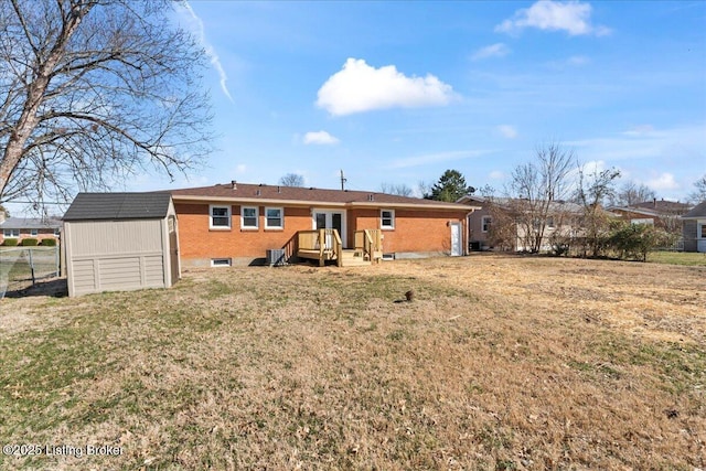 back of house featuring an outbuilding, fence, a shed, a yard, and brick siding