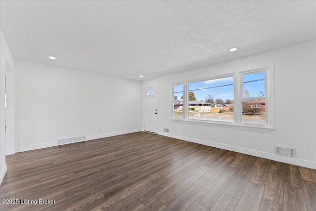 unfurnished living room featuring dark wood finished floors, visible vents, and baseboards