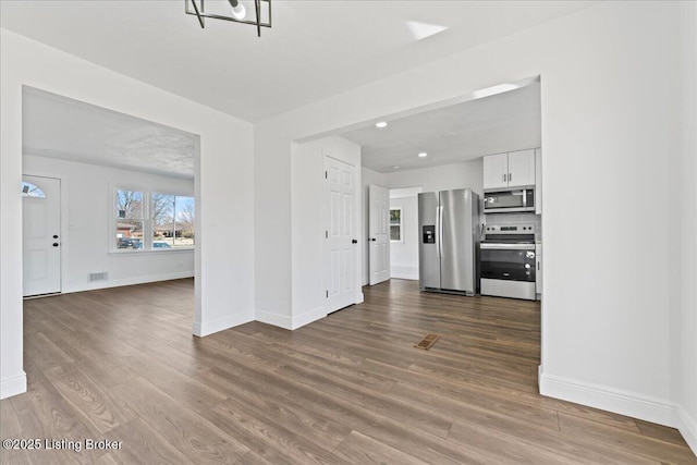 unfurnished living room featuring recessed lighting, wood finished floors, visible vents, and baseboards