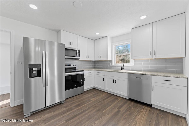 kitchen featuring dark wood finished floors, appliances with stainless steel finishes, white cabinetry, and a sink