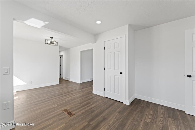 empty room featuring wood finished floors, visible vents, and baseboards