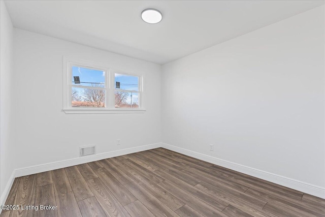 unfurnished room featuring visible vents, baseboards, and dark wood-type flooring