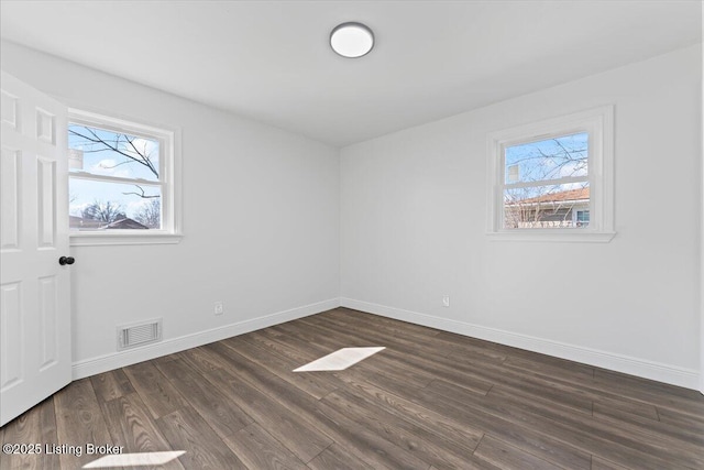 spare room featuring dark wood-style floors, visible vents, a healthy amount of sunlight, and baseboards