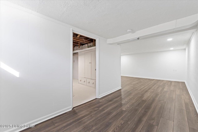 below grade area with visible vents, baseboards, a textured ceiling, and dark wood finished floors