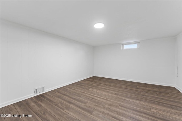 spare room featuring visible vents, dark wood-type flooring, and baseboards