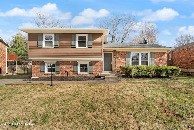 tri-level home with brick siding, a front yard, and fence