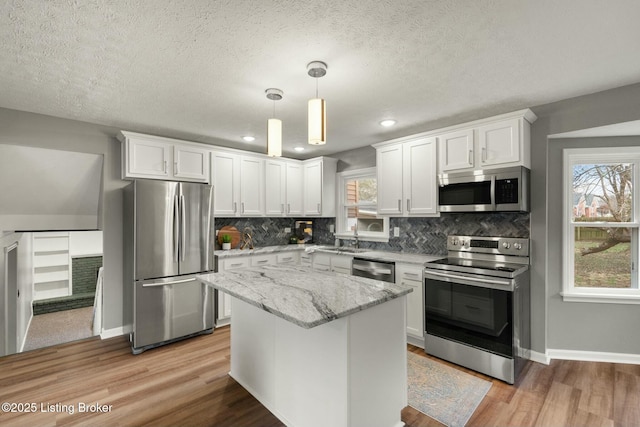 kitchen featuring stainless steel appliances, tasteful backsplash, plenty of natural light, and white cabinets