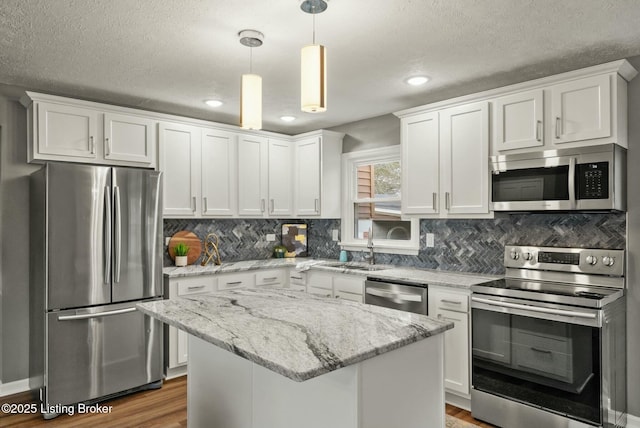 kitchen featuring white cabinetry, stainless steel appliances, a sink, and wood finished floors