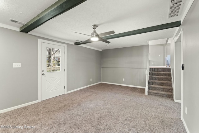 spare room with carpet floors, visible vents, ceiling fan, and stairs