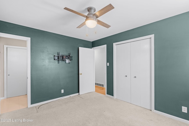 unfurnished bedroom with a ceiling fan, carpet, visible vents, and a closet