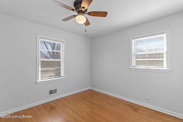 empty room with light wood finished floors, plenty of natural light, visible vents, and baseboards