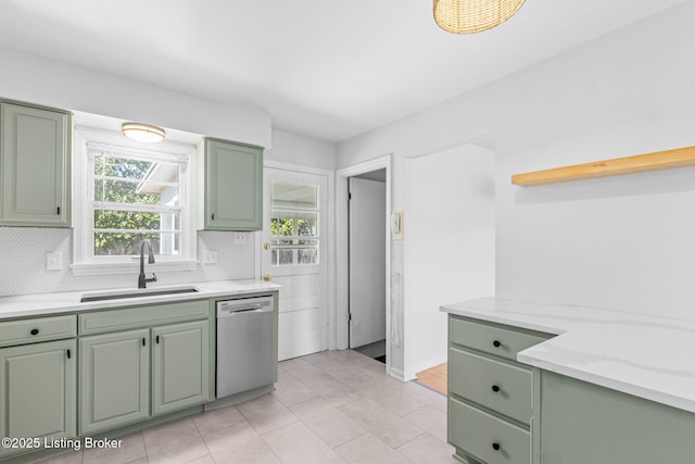 kitchen with stainless steel dishwasher, backsplash, a sink, and green cabinetry