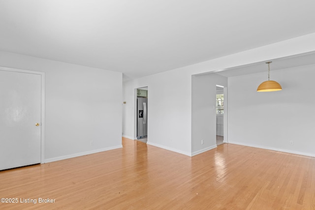 unfurnished room with light wood-type flooring and baseboards