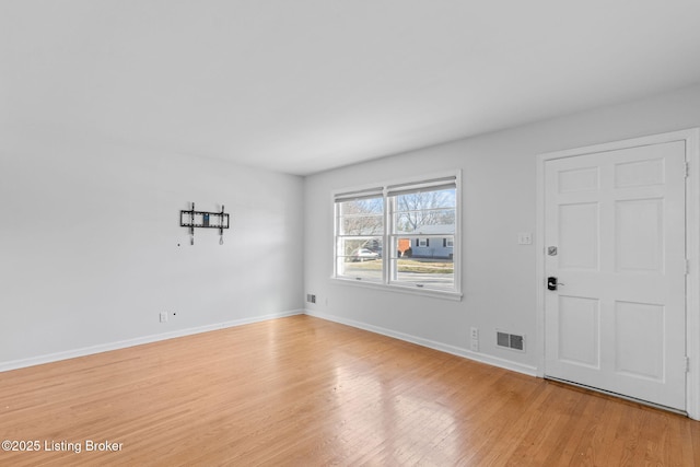 empty room featuring light wood-type flooring, visible vents, and baseboards