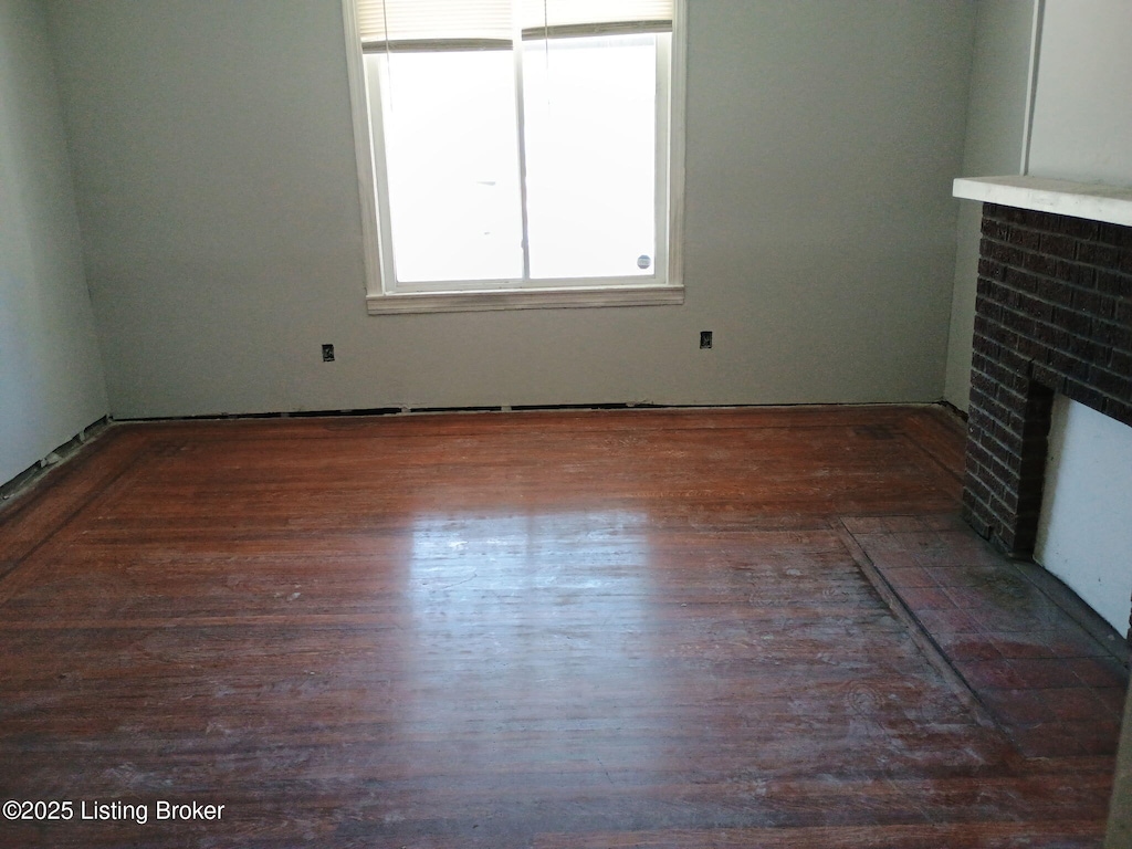 unfurnished living room with a brick fireplace and wood finished floors