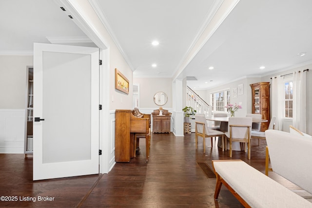 hallway featuring a wainscoted wall, plenty of natural light, stairs, and dark wood finished floors