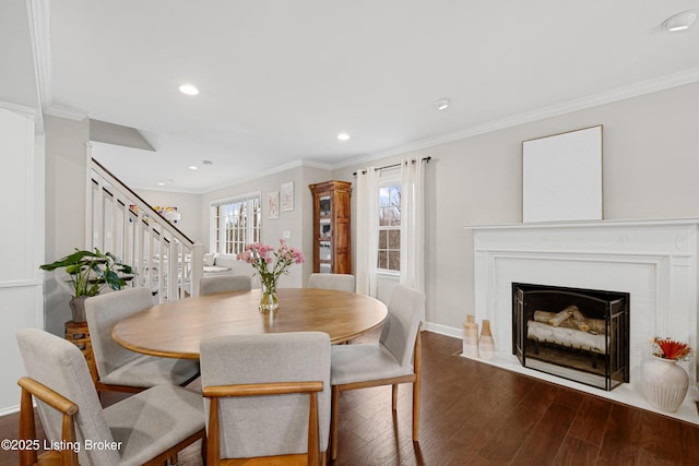 dining space featuring crown molding, dark wood finished floors, stairway, a fireplace with flush hearth, and baseboards