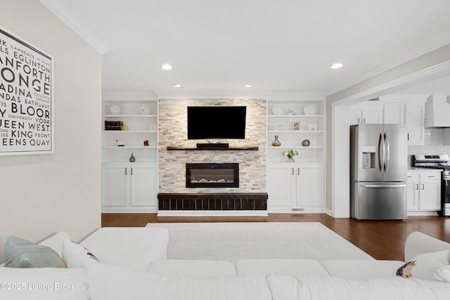 living room with built in shelves, dark wood finished floors, a fireplace, recessed lighting, and ornamental molding