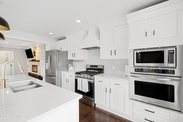 kitchen featuring dark wood finished floors, custom exhaust hood, decorative backsplash, appliances with stainless steel finishes, and a sink