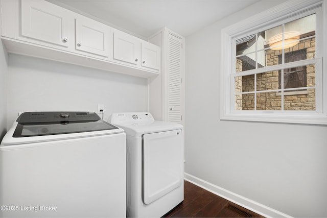 laundry room with washing machine and dryer, visible vents, baseboards, cabinet space, and dark wood finished floors