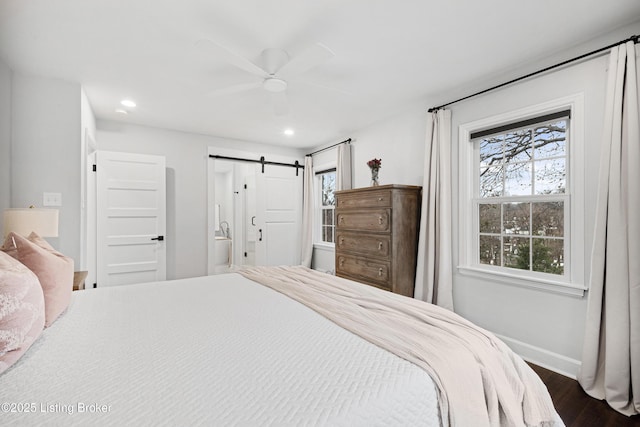 bedroom featuring recessed lighting, dark wood-style flooring, baseboards, and a barn door