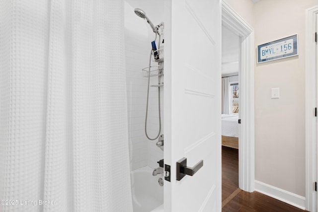 bathroom with wood finished floors, shower / bath combo with shower curtain, and baseboards